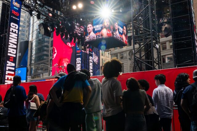 People gather around the outdoor boxing ring erected in Times Square for the fight card fe