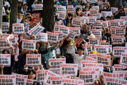 People hold placards that read "Let's not forget the December 3 insurrection" during a cam