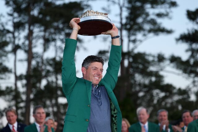 World number two Rory McIlroy of Northern Ireland lifts the Masters trophy while wearing t