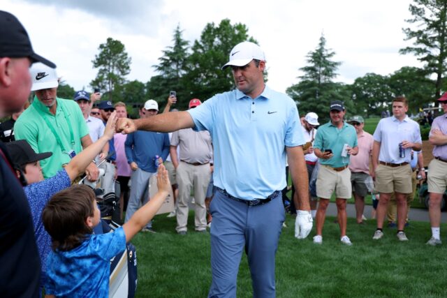World number one Scottie Scheffler of the United States fist-bumps young fans during a pra