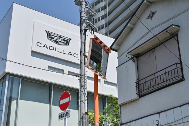 A sign for Cadillac cars is displayed on the outside wall of a car dealership which sells