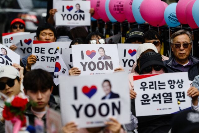 Supporters of South Korea's ex-president Yoon Suk Yeol hold up placards during a gathering