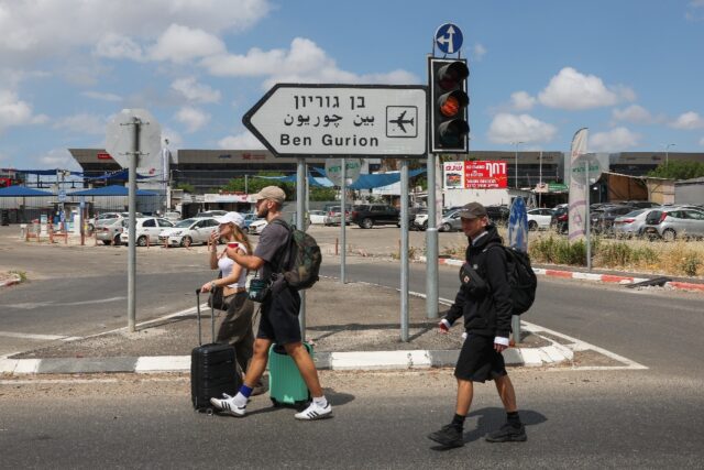 Travellers enter Israel's Ben Gurion airport after air defences were activated against a m