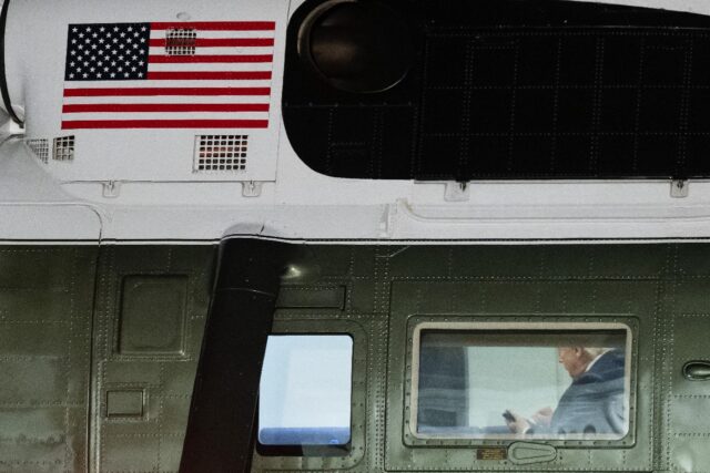US President Donald Trump looks at his cellphone aboard Marine One
