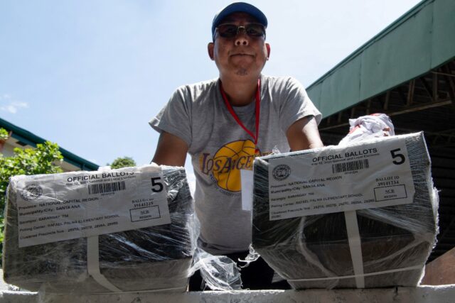 A worker prepares to unload ballots at a polling station Sunday in Manila on the eve of th