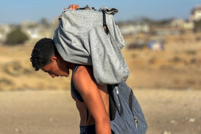 A youth carries a package on his back after Palestinians received food from a US-backed fo