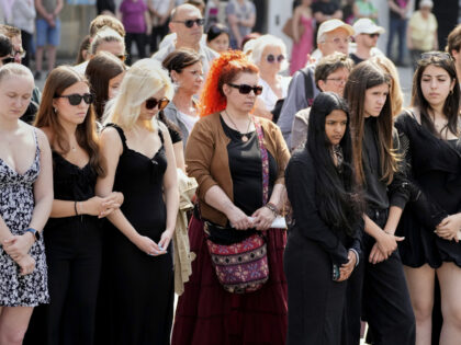 People pay a moment of silence on the main square after a former student opened fire the d
