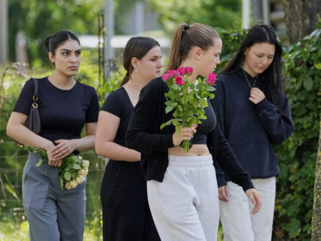 Women with flowers arrive at a school where a former student opened fire two days before,