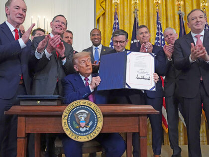 President Donald Trump holds up a signed bill blocking California's rule banning the sale