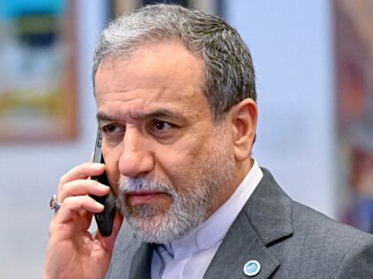 ran foreign minister Abbas Araghchi talks on his mobile phone ahead the family photo durin