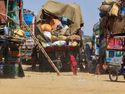 Afghan refugee children play next to trucks loaded with their family's belongings as