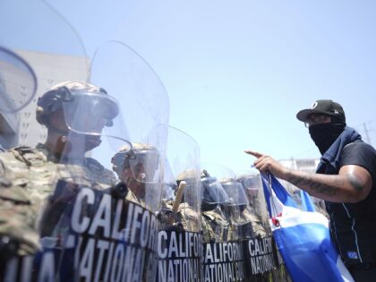 Un manifestante se enfrenta contra una fila de agentes de la Guardia Nacional de Estados U