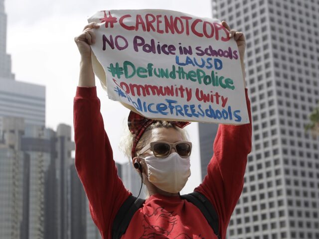 FILE - A demonstrator holds a sign in front of the downtown skyline during a protest to de
