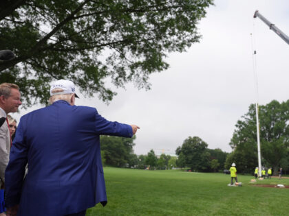 President Donald Trump looks on as a flag pole is installed on the South Lawn of the White