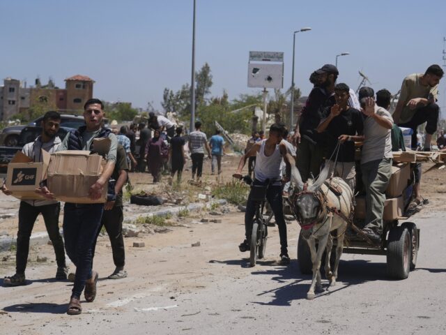 Palestinians carry boxes and bags containing food and humanitarian aid packages delivered