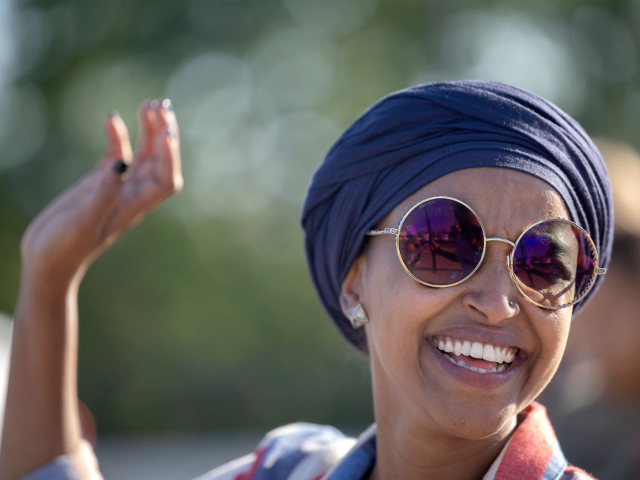 U.S. Rep. Ilhan Omar waves to passerbys for support during a voter engagement event on the