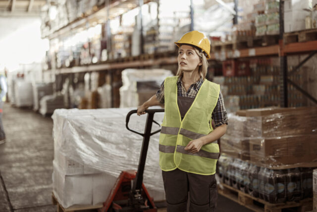 Female warehouse manager pulling a pallet truck