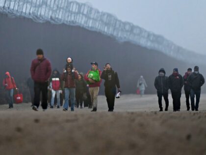 JACUMBA HOT SPRINGS, CALIFORNIA - DECEMBER 22: Migrants walk along the US-Mexico border fe