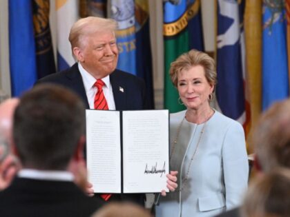 U.S. President Donald Trump holding up a signed executive order poses with U.S. Education