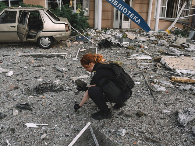 A police officer collects drone missile parts at the site of a Russian overnight attack in