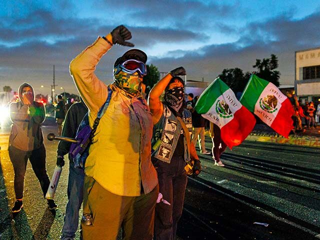 Protesters continue to march towards a law enforcement line as Los Angeles residents push