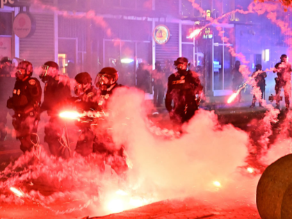 Fireworks explode around police officers in riot gear during a protest in response to fede