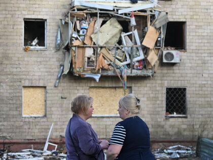 TOPSHOT - Women stand near a damaged residential building following a Russian drone strike