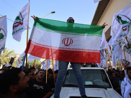 A man holds the Iranian flag as supporters of Iraqi pro-Iran groups demonstrate in Baghdad