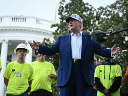 US President Donald Trump speaks to the press as workers install a large flag pole on the