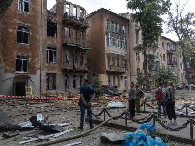Local residents look at damaged residential buildings following the Russian drone attack i