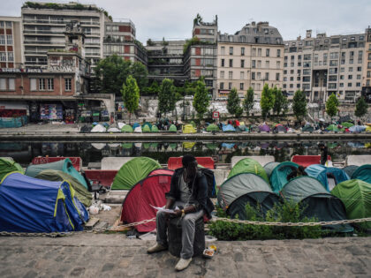 TOPSHOT - A man sits as migrants prepare their belongings at the start of the evacuation b