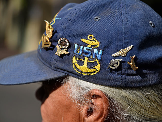 A U.S. Navy veteran wears a cap embellished with service medals and military memorabilia a