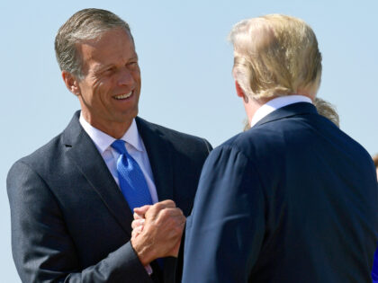 President Donald Trump, right, is greeted by Sen. John Thune, R-S.D., left, after arriving