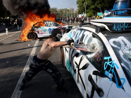 Los Angeles, CA. June 8, 2025 A protester damages a Waymo vehicle at Los Angeles St. and A