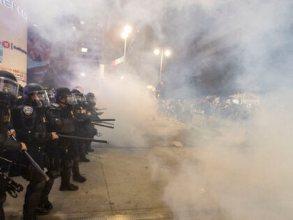 Police officers in riot clash with demonstrators during a protest following federal immigr