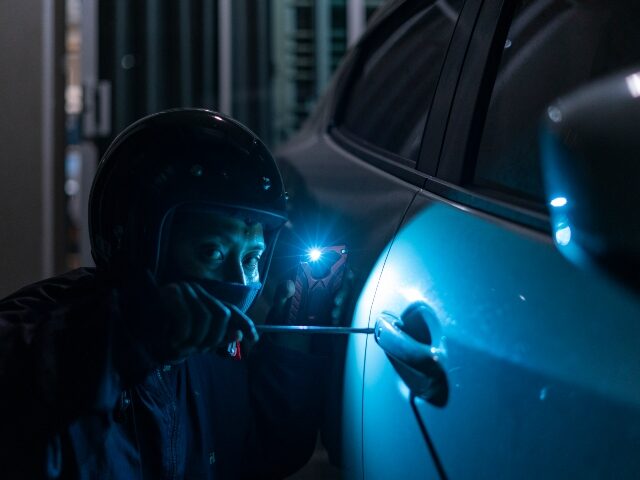 Car thief breaking into a vehicle.