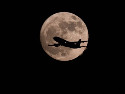 BEIJING, CHINA - JUNE 10: A passenger plane flies in front of the full strawberry moon ove