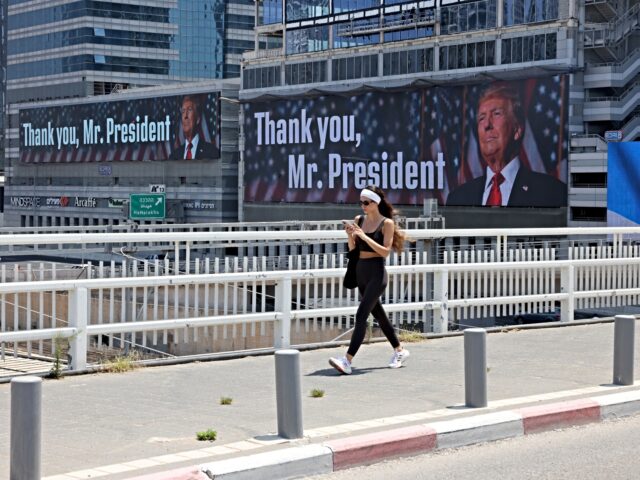 A woman walks on a bridge in front of banners bearing a pictures of US President Donald Tr