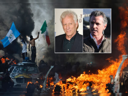 LOS ANGELES, CALIFORNIA - JUNE 08: Protestors wave flags as burning and vandalized Waymo c