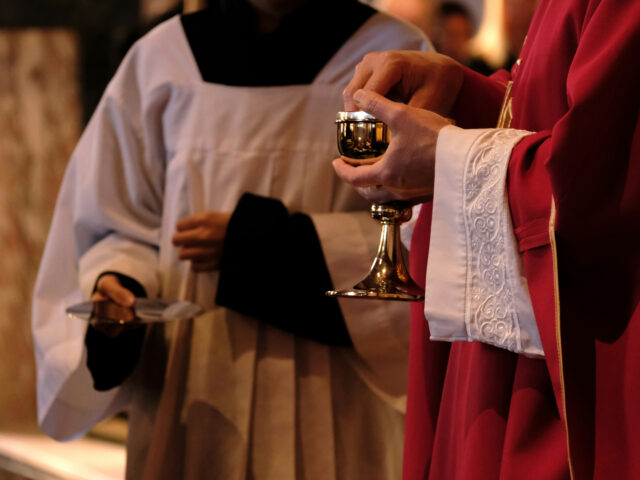 A priest is holding a chalice in a church