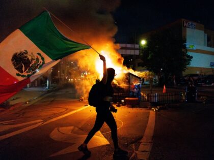 LOS ANGELES, CA - JUNE 8, 2025: A demonstrator waves a Mexican flag in front of a dumpster