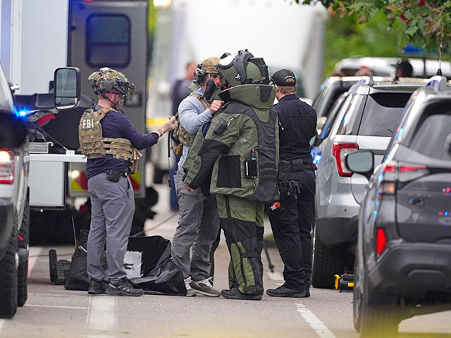 Law enforcement officials dress up in protective gear to investigative an attack on the Pe