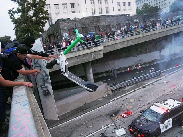 L.A. Pritzker - A protester throws a scooter at a police vehical near the metropolitan det