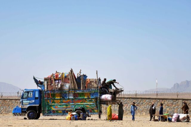 Afghan refugees unload their belongings from a truck upon their arrival from Pakistan in M