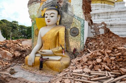 A man clears debris around a quake-damaged Buddha statue at Lawkatharaphu Pagoda in Inwa.