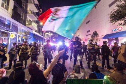 Demonstrators waving a Mexico flag confront police officers during a demonstration against