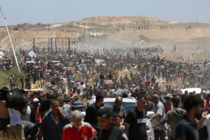 Displaced Palestinians carrying relief supplies return from an aid distribution centre in