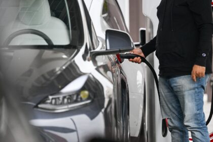A driver plugs in a Tesla electric vehicle to charge at a Tesla Supercharger location in S