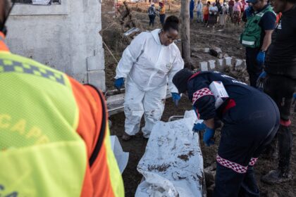 Forensics personnel write on a body bag after finding victims of the flooding near Mthatha