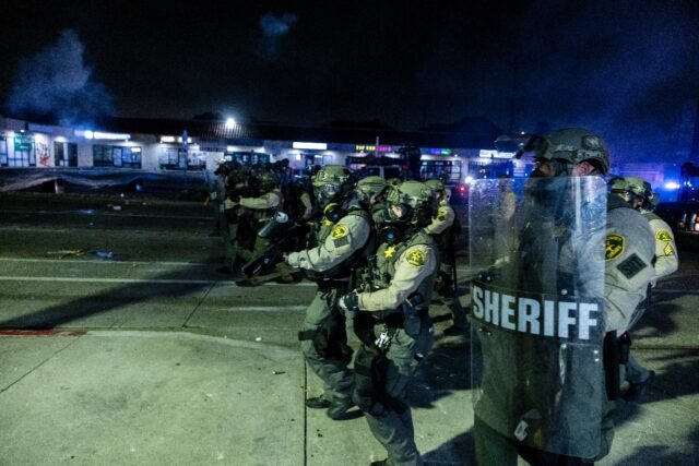 Law enforcement clash with demonstrators during a protest following federal immigration op